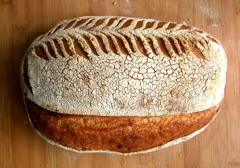 Sourdough batard scored with a repeating chevron wheat-stalk pattern